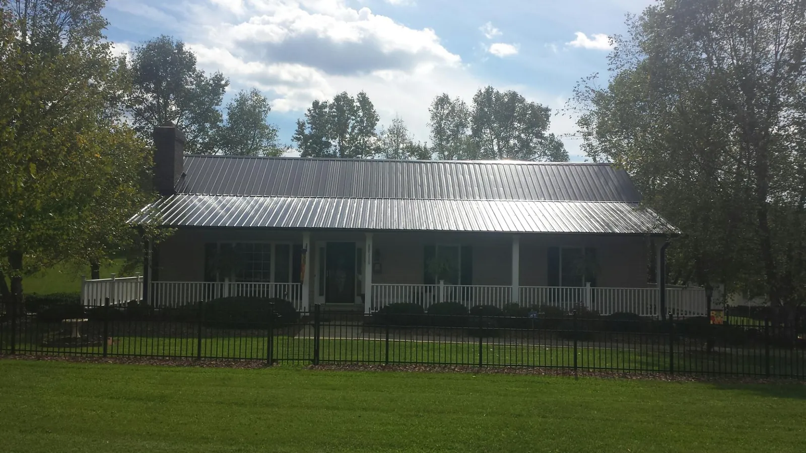Gray metal roof on a brick ranch with a full width front porch — Gutter Guard Installation work by our crew in East Rochester